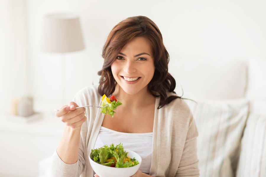 Smiling Young Woman Eating Salad at Home