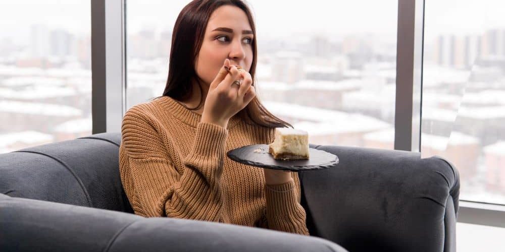 Woman eating cake. According to studies, people do eat more during the winter months.