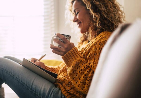 Smiling woman writing journal entry.