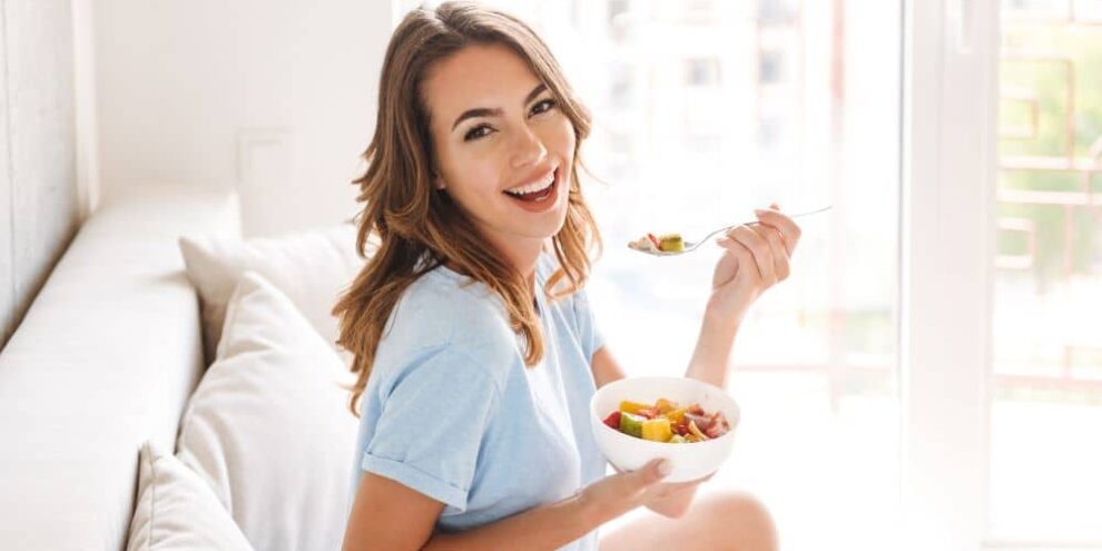 Smiling young woman eating a healthy breakfast.